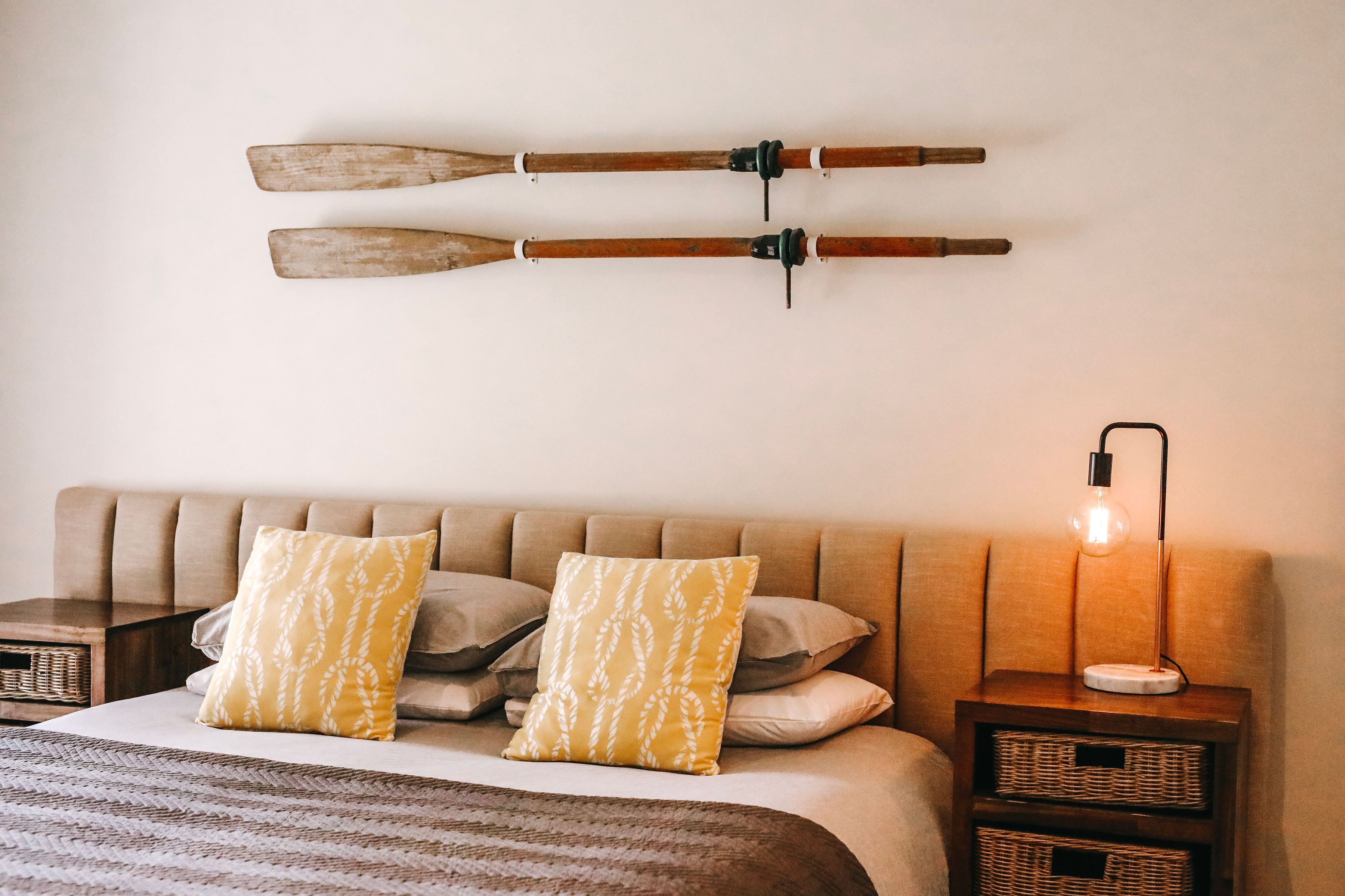 A neatly arranged bedroom with a bed, pillows, a bedside table, and a wall-mounted lamp.