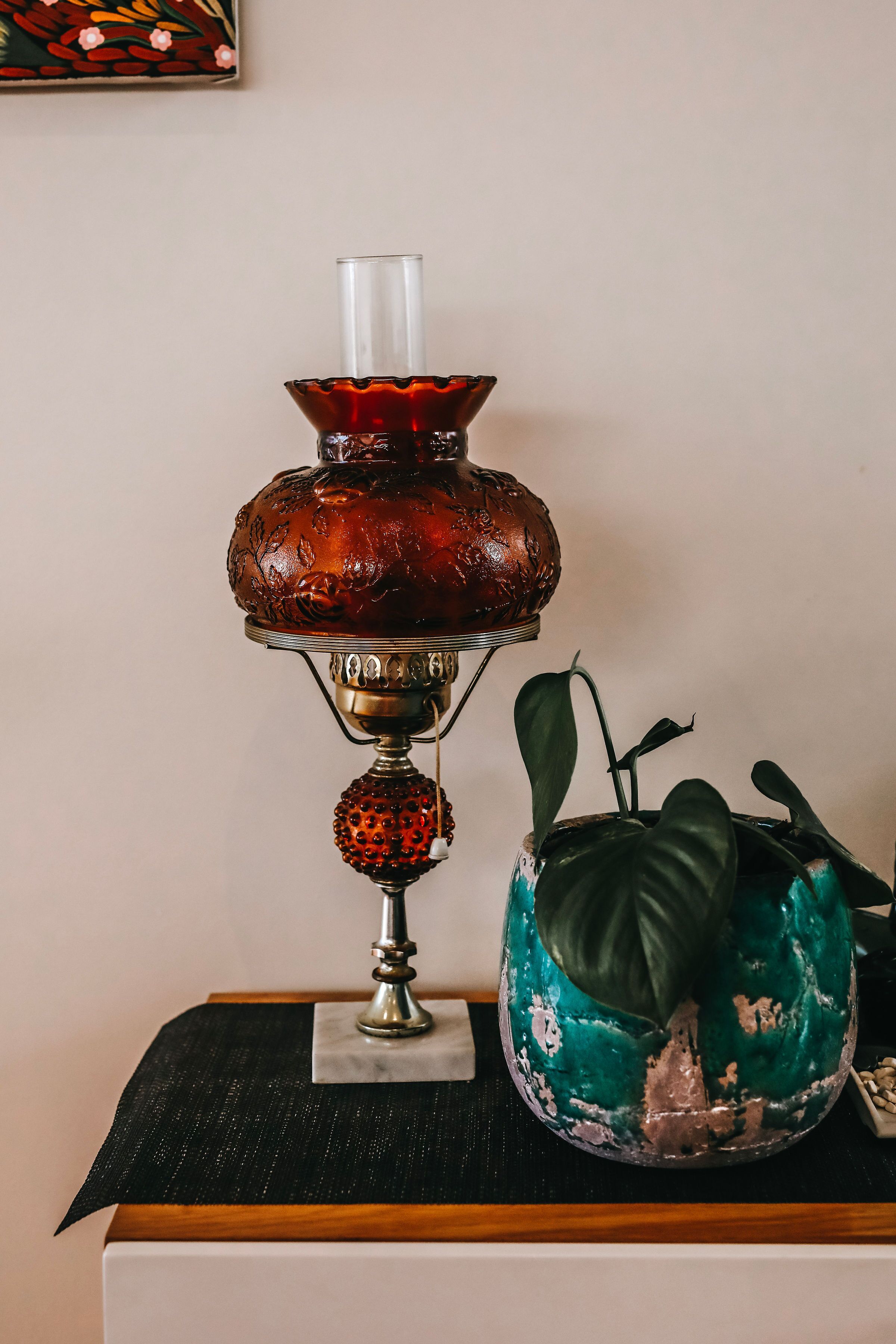 A table with a decorative lamp and a potted plant.