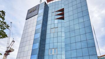 A modern hotel with a glass facade, a prominent entrance, and a construction crane nearby.