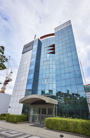 A modern hotel with a glass facade, a prominent entrance, and a construction crane nearby. - Hotel Interciti (Daejeon)