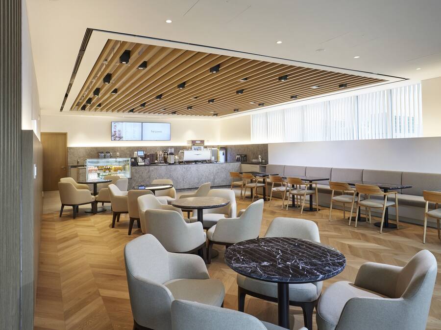 Un café moderno con techo de madera, asientos cómodos y una zona de mostrador visible.