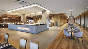 Un lobby moderno de hotel con una zona de bar central, arreglos de asientos y un mostrador de recepción de madera.