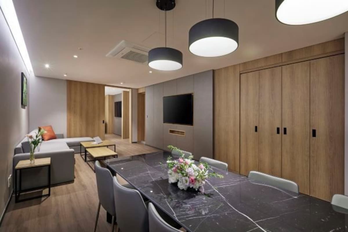 A modern conference room with a marble table, grey chairs, a sofa, and a TV screen.