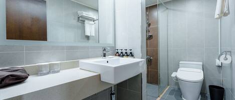 A modern bathroom with a white sink, mirror, and toilet.