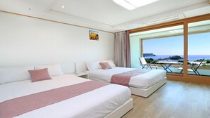 A hotel room with two beds, a large window with a view of the beach, and a small table with chairs. - Marine Port Resort (Seogwipo)