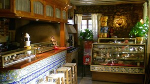 Un café acogedor con mostradores de madera, paredes de azulejos y una vitrina con pasteles.