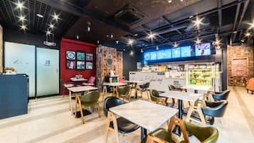 Un café moderno con mesas y sillas, una barra con un menú, y una pared decorada con fotografías.