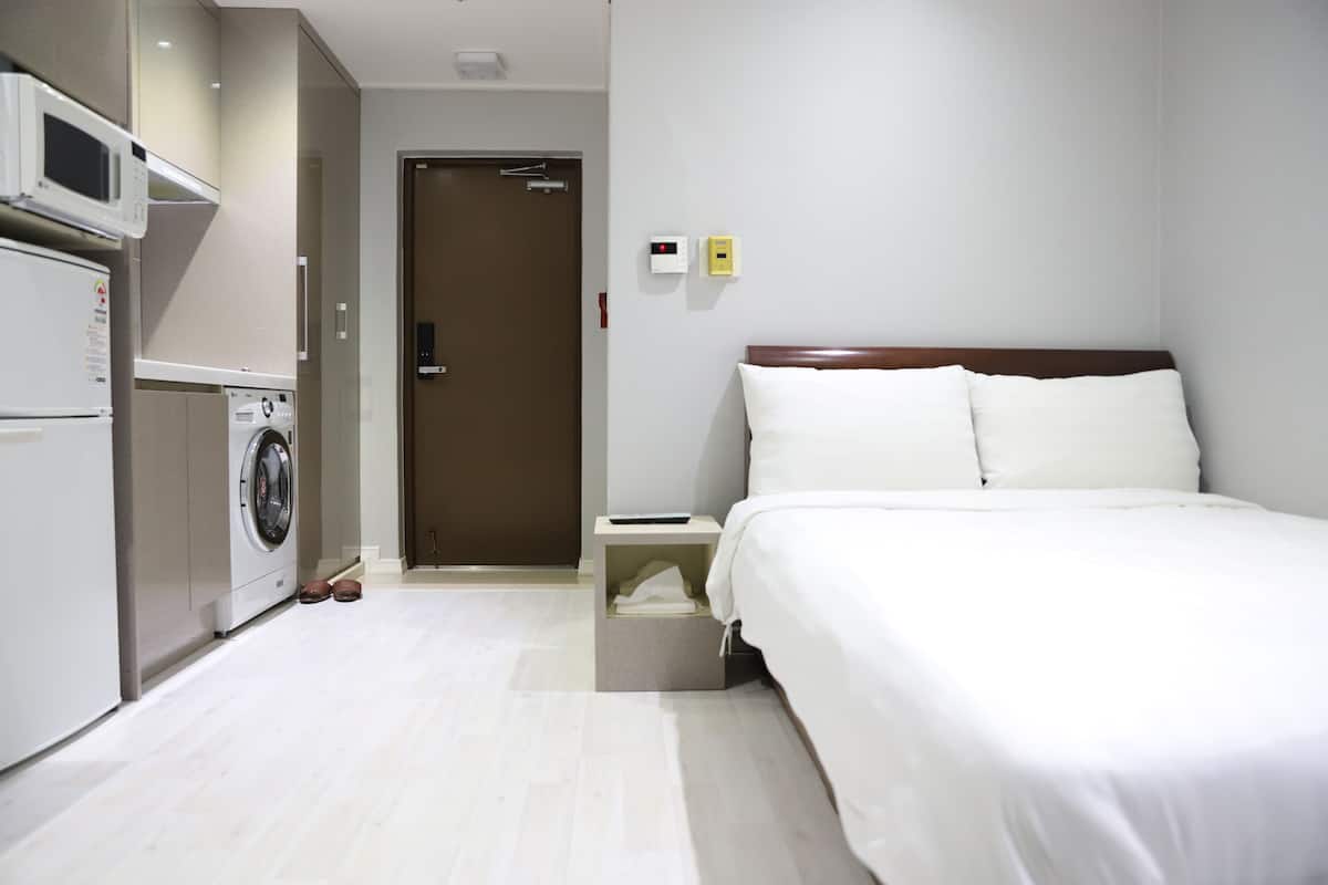 A hotel room with a bed, a washing machine, and a microwave.