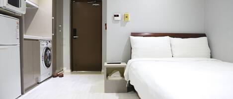 A hotel room with a bed, a washing machine, and a microwave.