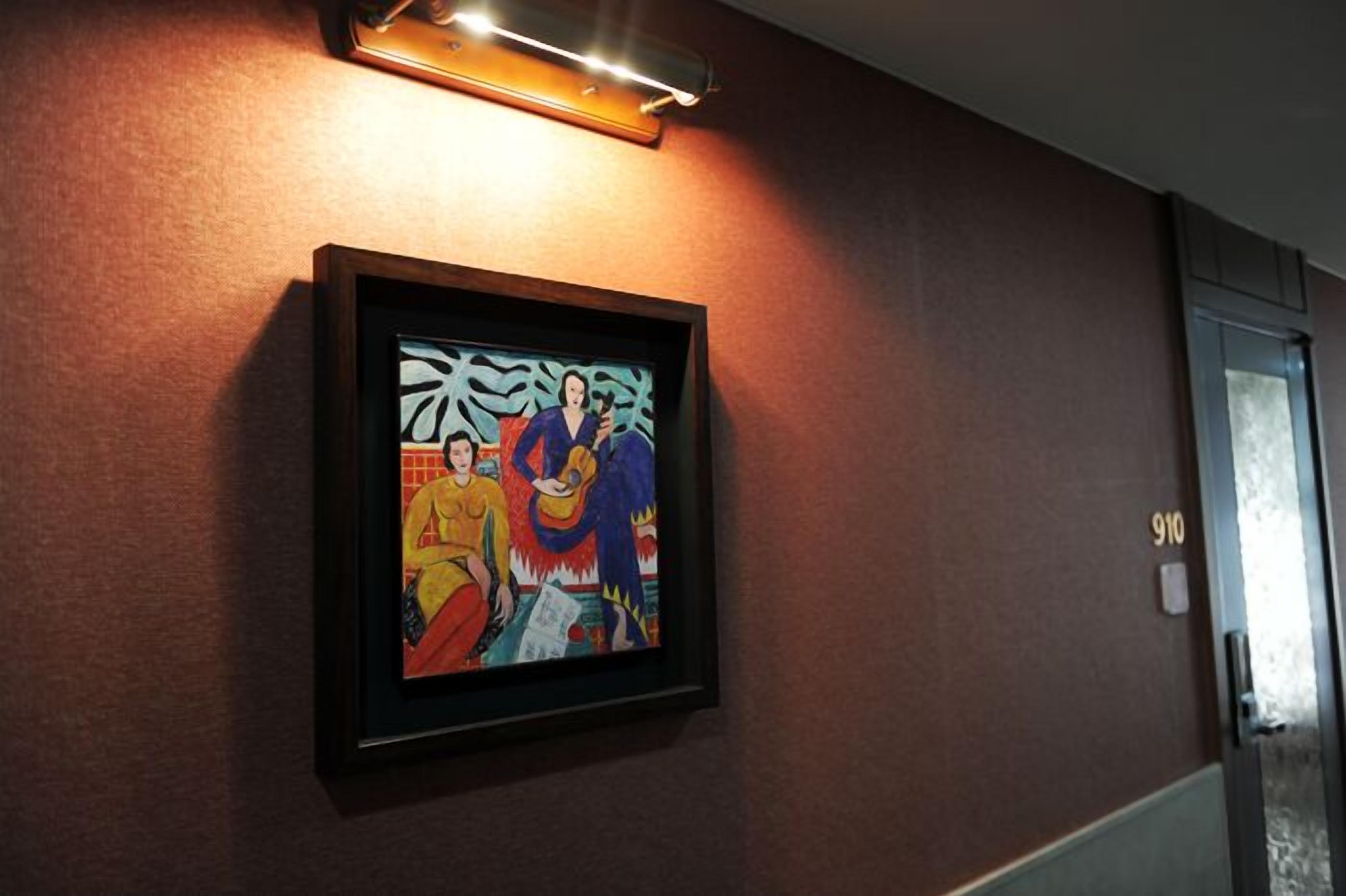 A framed artwork on a wall with a door labeled "910" to the right.