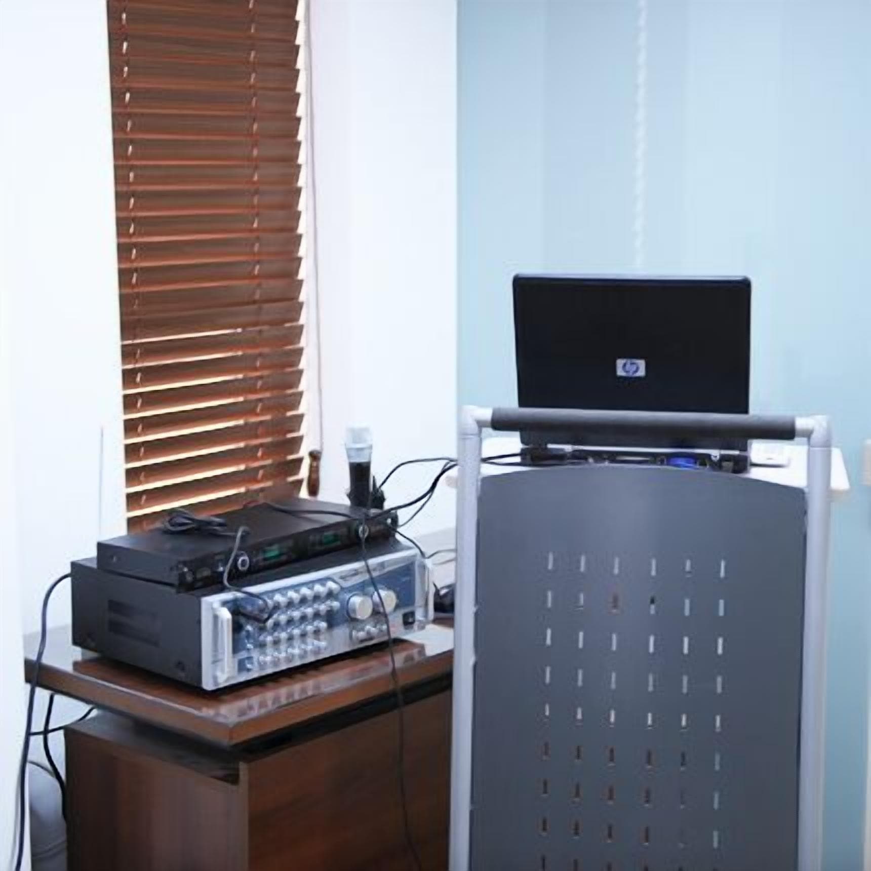 Quarto com escrivaninha, laptop e equipamento de áudio.