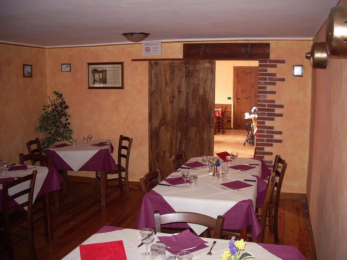 Comedor con mesas dispuestas para cuatro, sillas de madera y pared de ladrillo.