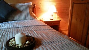A neatly made bed with a pillow, a bedside table with a lamp, and a tray with nuts and a candle. - Locanda Aquila Bianca (Valprato Soana)