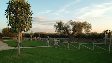 Guests can enjoy a serene outdoor setting with a well-maintained lawn and a variety of trees, including a prominent one with dense foliage.