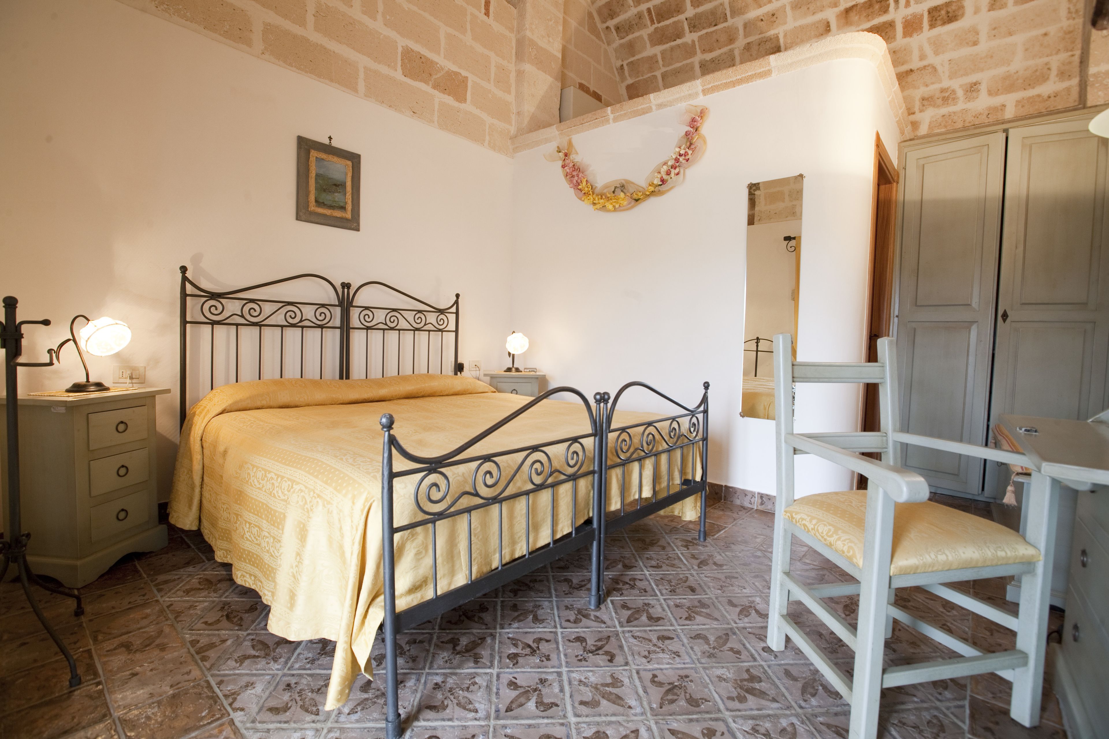 Quarto com cama, mesas de cabeceira, uma cadeira e um guarda-roupa.