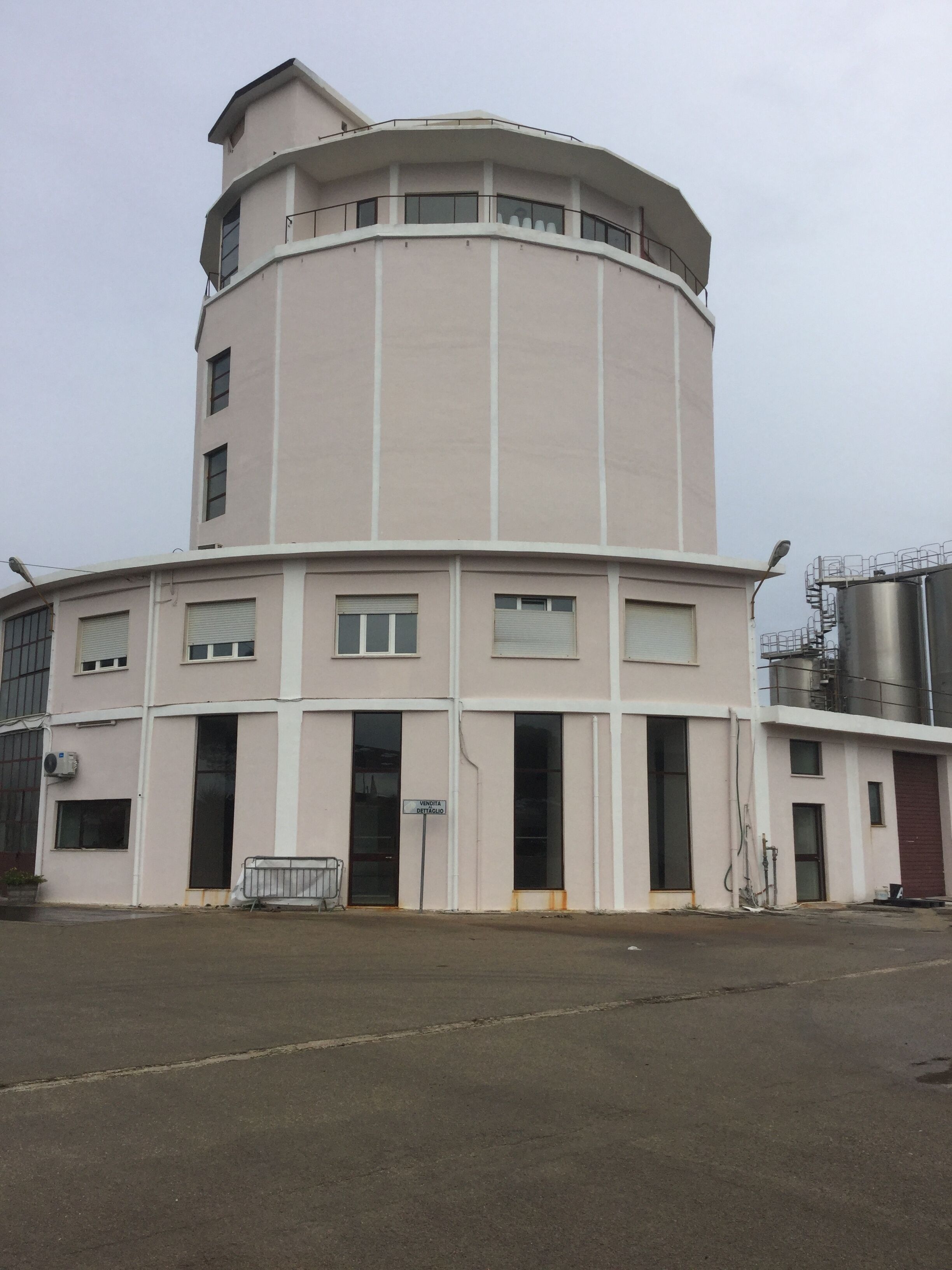 Ein mehrstöckiges Industriegebäude mit einer gebogenen Fassade, großen Fenstern und einem flachen Dach.