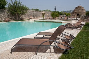 A pool area with lounge chairs and a stone wall.