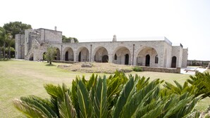 Un edificio de piedra con varios arcos y un patio cubierto de césped.