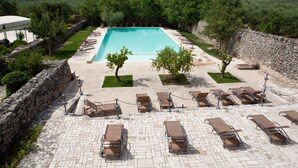 Un área de piscina con sillones de descanso y una pared de piedra.