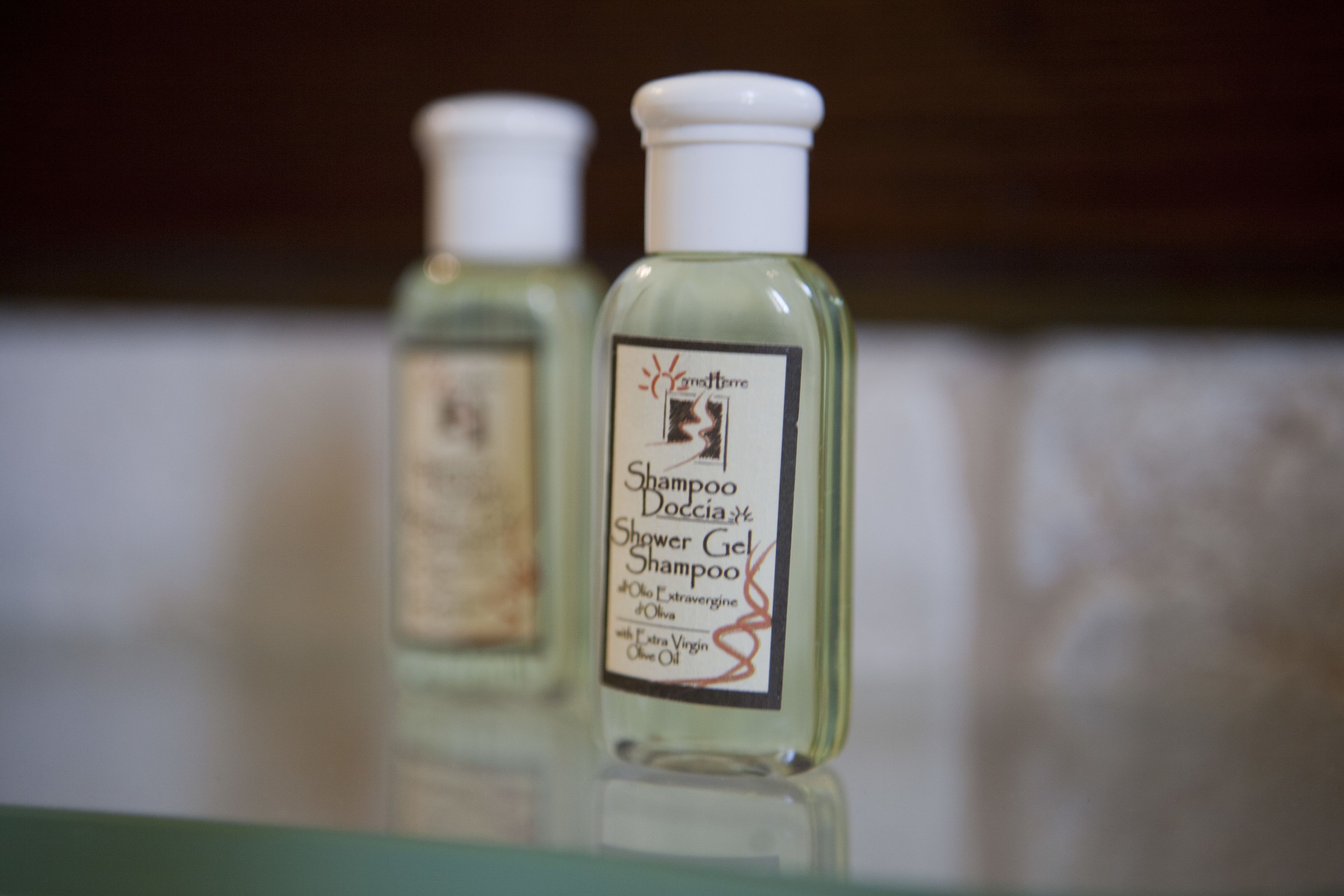 Two bottles of shampoo and shower gel on a reflective surface.