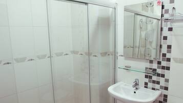 A modern bathroom with a glass-enclosed shower, a pedestal sink, and a toilet.