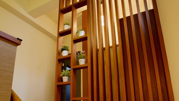 A staircase with wooden steps and a wooden railing with shelves holding potted plants. - Soft Travel Hostel (Taitung)