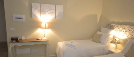 A hotel room with two beds, a bedside table, a lamp, and wall art.