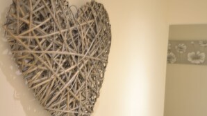 Een kamer met een groot abstract kunstwerk aan de muur, een lichtgekleurde vloer en een gedeeltelijk zicht op een behang met patroon.