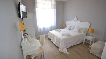 A hotel room with a bed, bedside tables, a desk, and a chair.