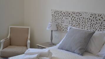 Habitación de hotel ordenada con cama, una silla, una mesita de noche y un cabecero decorativo.