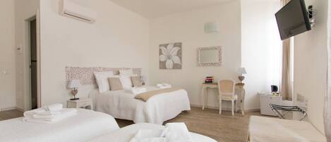 A hotel room with two beds, a desk, a chair, a TV, and a window with curtains.