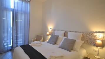A hotel room with a large bed, two bedside tables with lamps, a chair, and a window with curtains.