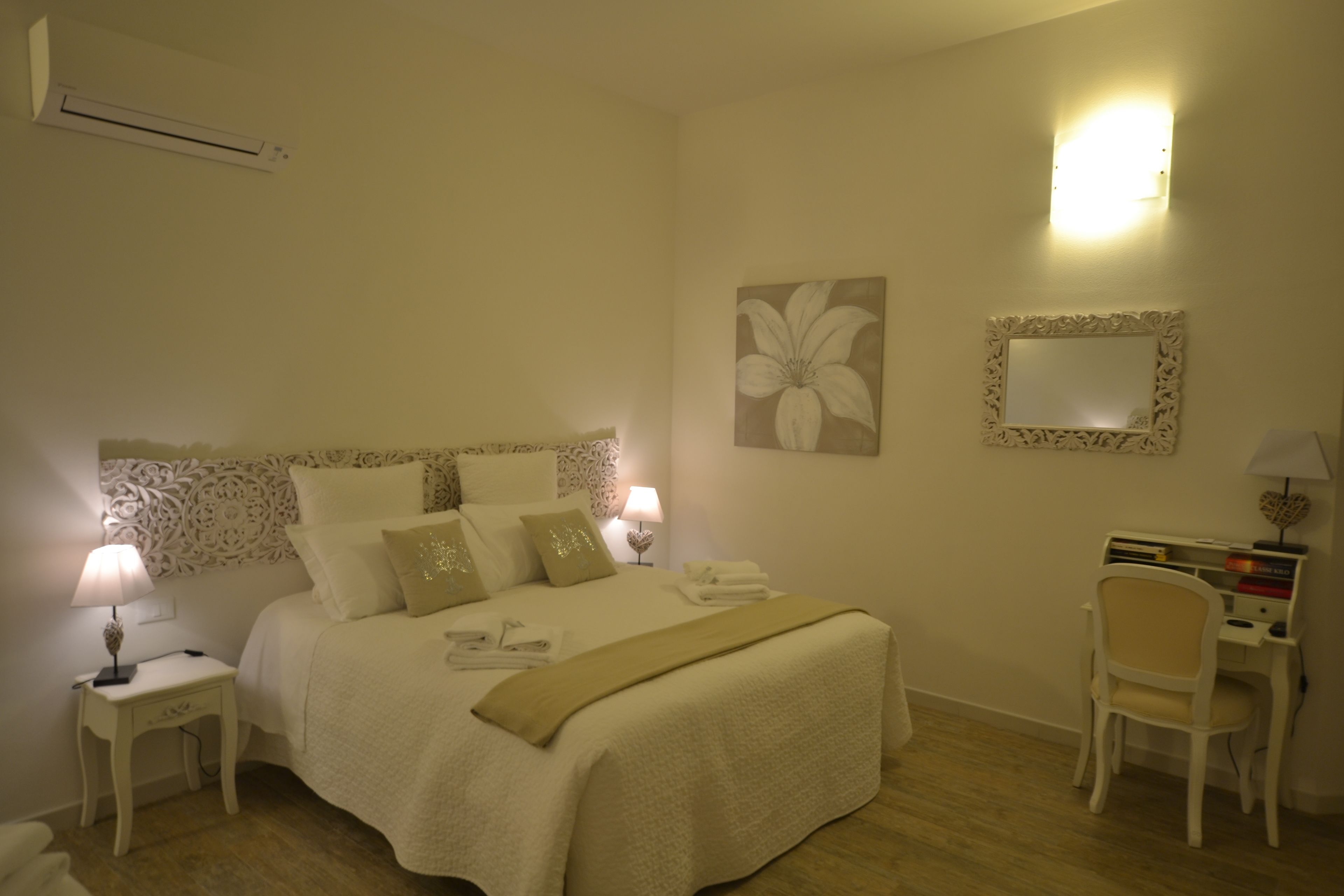 A bedroom with a bed, bedside tables, a desk, and a chair.