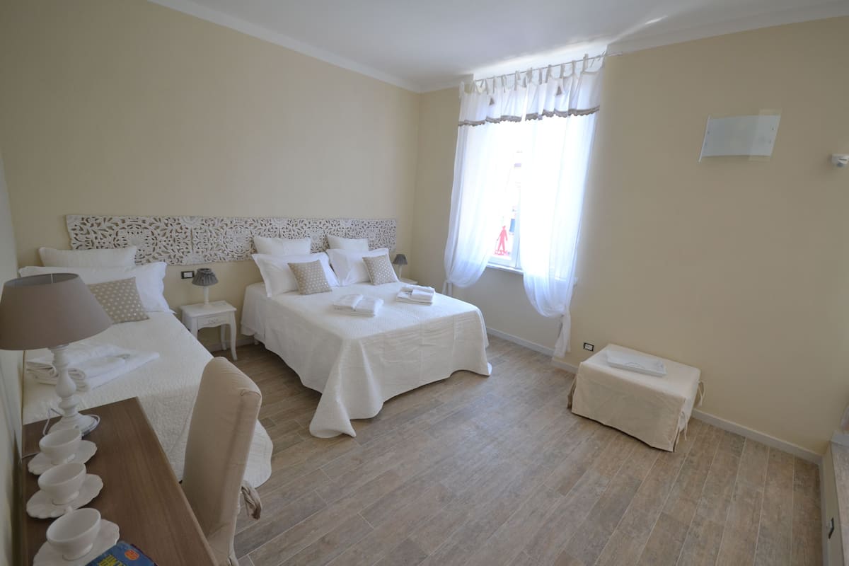 Une chambre d’hôtel avec deux lits, une petite table avec une lampe, une chaise et une fenêtre avec des rideaux.