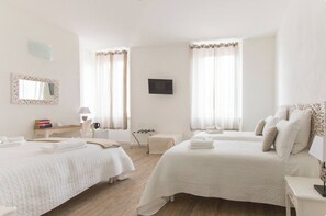 A hotel room with two beds, a TV, a desk with a lamp, and a mirror.