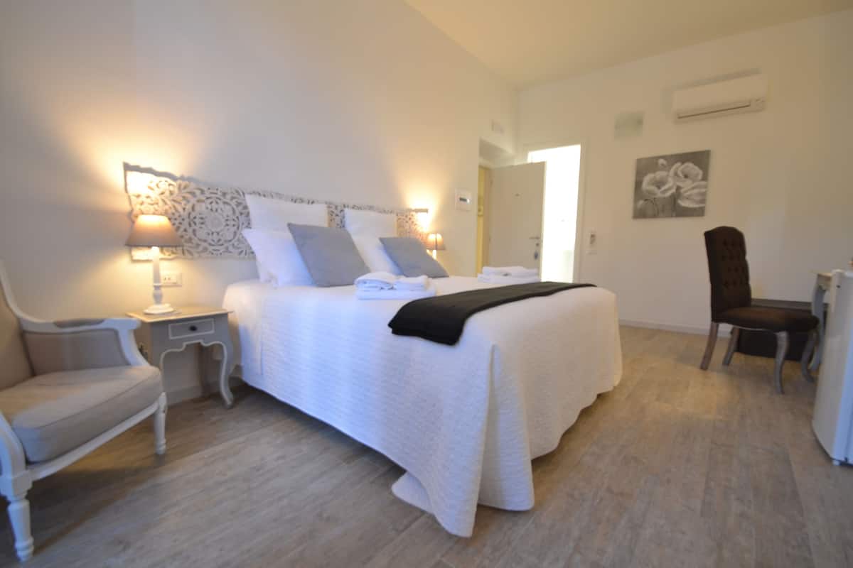 Une chambre d’hôtel avec un lit, des tables de chevet, une chaise et un bureau.