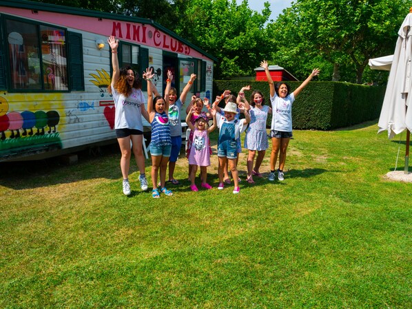Un grupo de niños de pie frente a un autobús colorido con el texto "MINI CLUB".