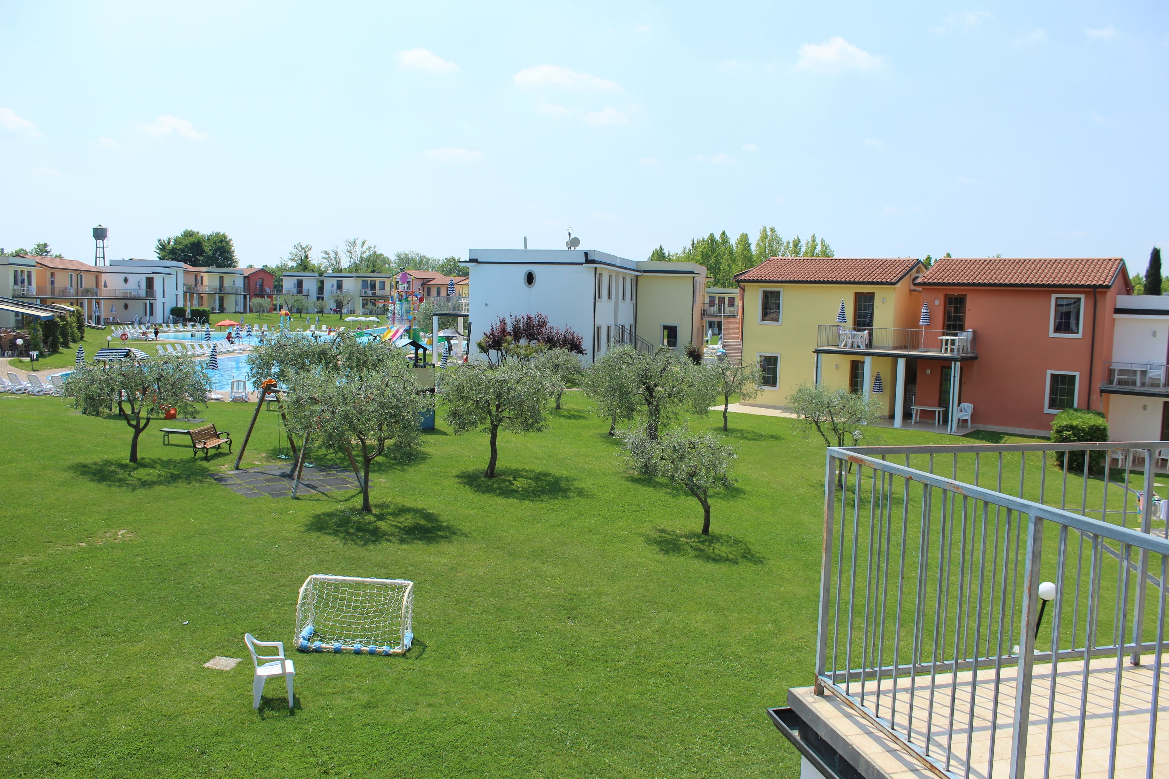 Ett bostadsområde med en swimmingpool, små träd och en lekplats.