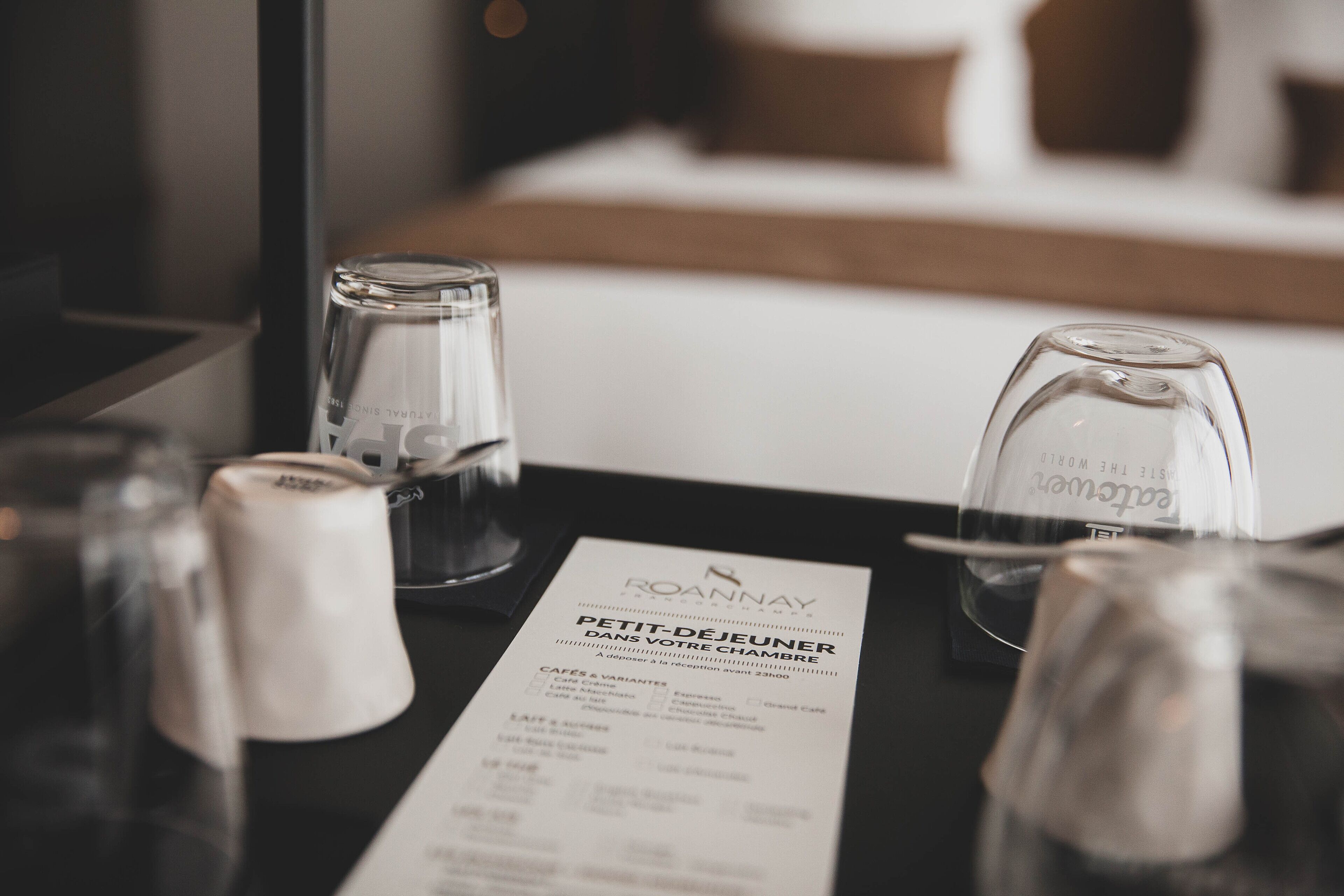 A hotel room with a minibar, a glass of water, and a menu on the table.