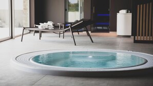 A modern indoor pool area with a hot tub, lounge chairs, and a view through large windows. - Roannay – Francorchamps (Stavelot)
