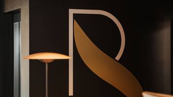 Un comptoir d’accueil moderne au design minimaliste, agrémenté d’un grand logo abstrait sur le mur qui le surplombe.