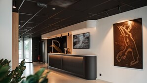 A modern reception area with a curved counter, a large abstract painting, and a digital sign indicating the location. - Roannay – Francorchamps (Stavelot)