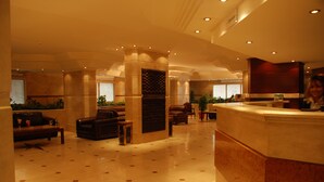 Un vestíbulo espacioso con mostrador de recepción, zona de estar y plantas decorativas.