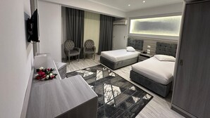 Una habitación de hotel moderna con dos camas, un escritorio, un televisor y un ventanal grande.