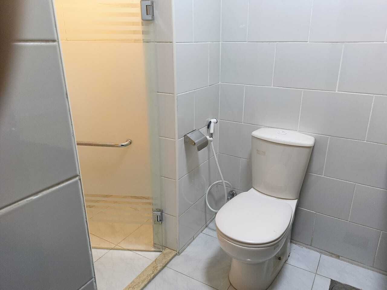 A small bathroom with a toilet, a shower area, and a towel rack.