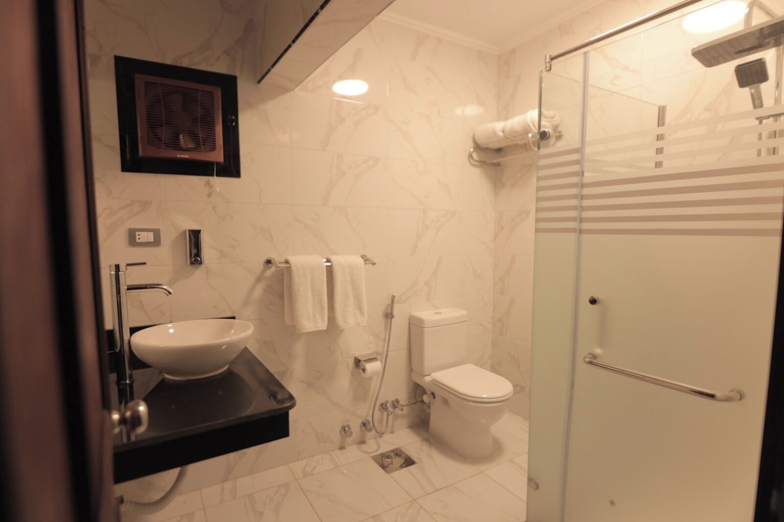 A modern bathroom with a sink, toilet, and glass shower enclosure.