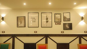 Un vestíbulo de hotel con obras de arte enmarcadas en la pared, un banco de madera con asientos acolchados e iluminación en la pared.