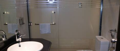 Une salle de bain moderne avec un lavabo blanc, des toilettes et une douche à parois de verre.