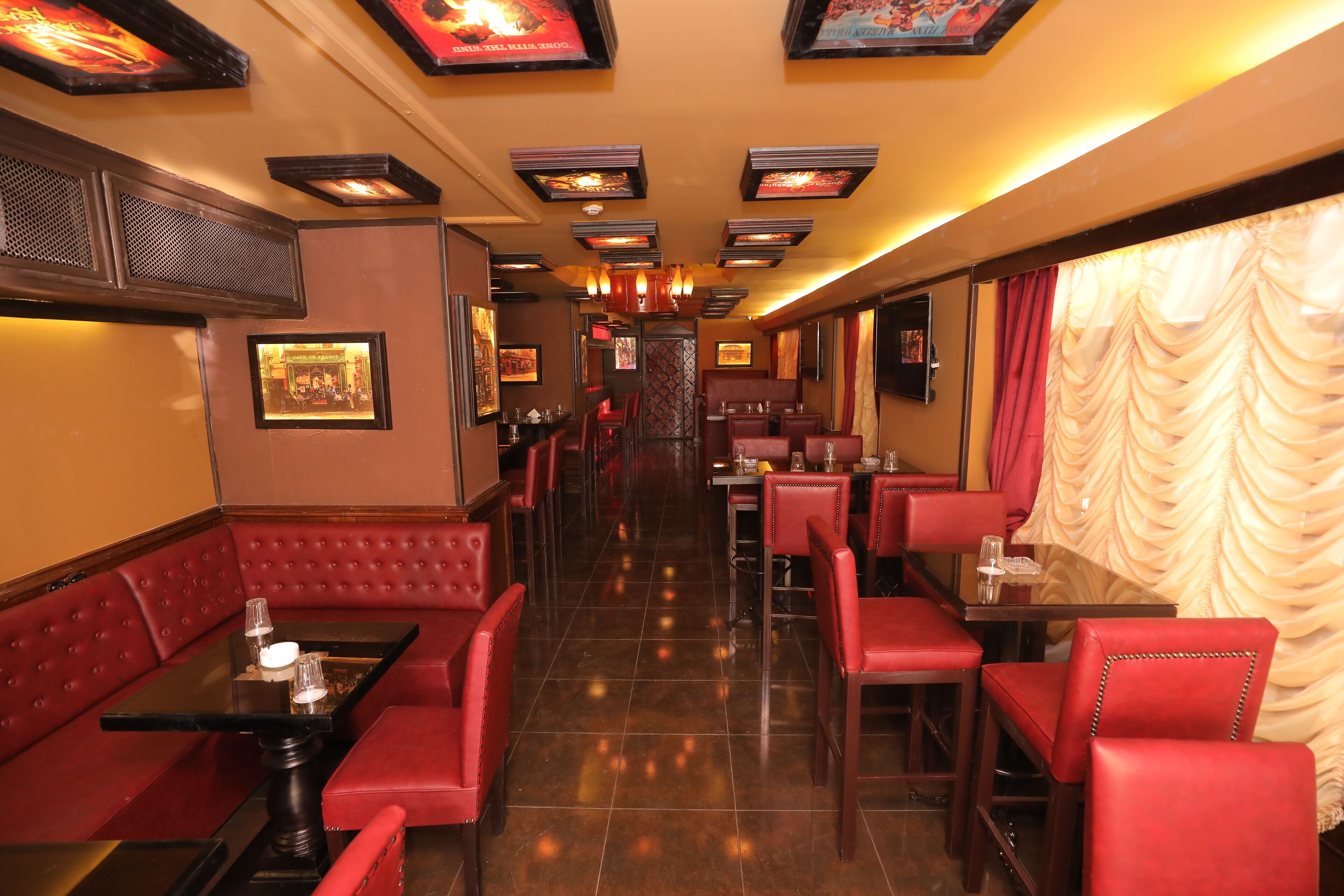 A restaurant with red booths and tables, framed pictures on the walls, and a tiled floor.