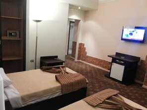 A hotel room with two beds, a desk, a television, and a small refrigerator. - Aura Inn Hotel Cairo (Giza)